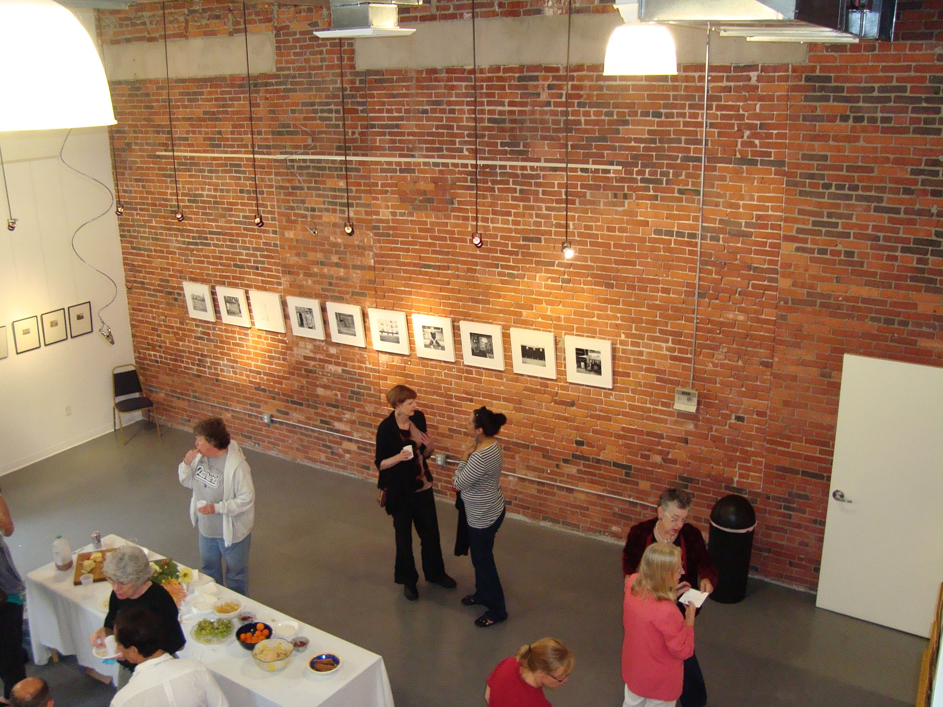 Visitors viewing artwork along the exposed brick wall of the Spencer Lofts Gallery in 2010