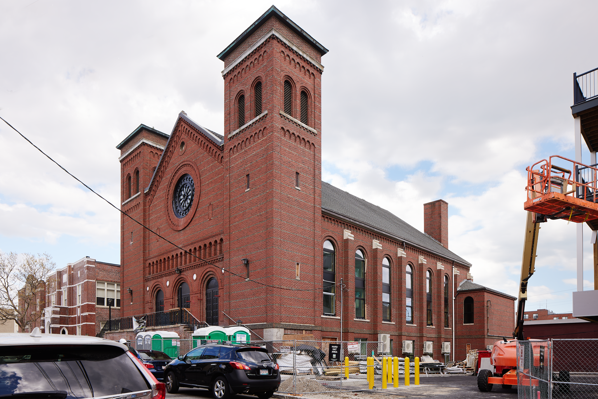 Brick church front with twin towers and rose window under construction at 163 Chestnut Street in Chelsea, Massachusetts