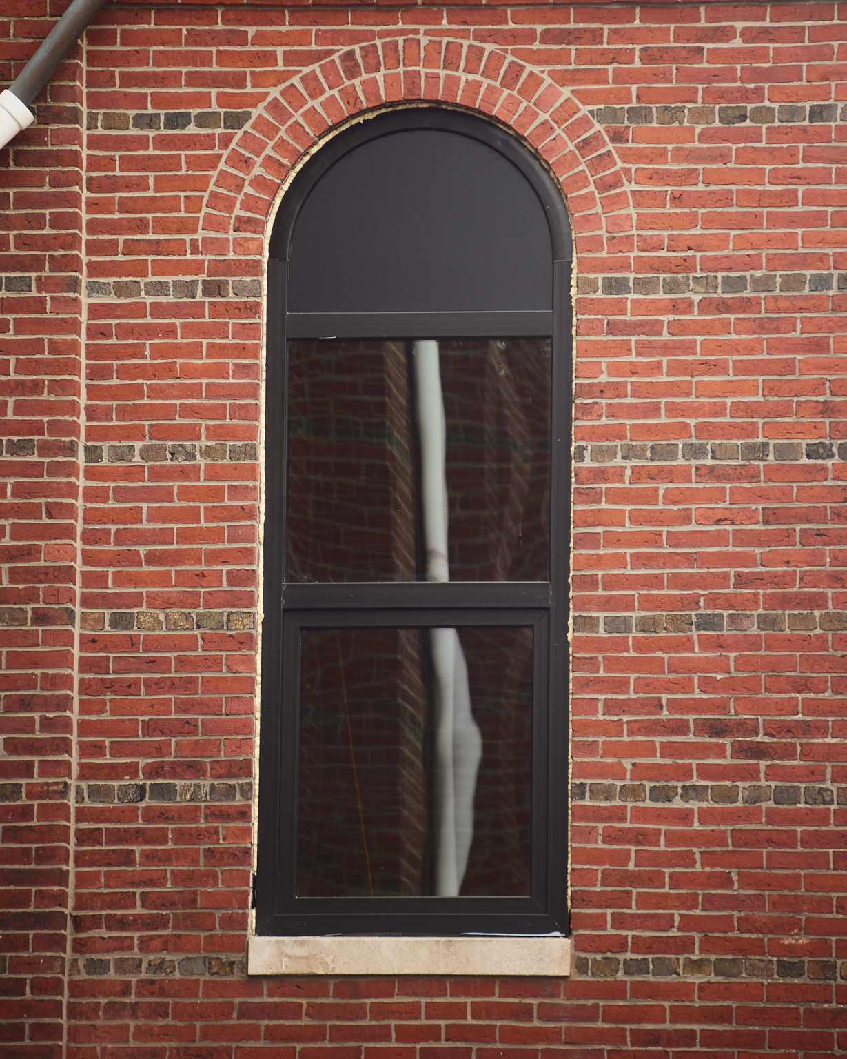 Arched window with black frame on the brick church at 163 Chestnut Street in Chelsea, Massachusetts
